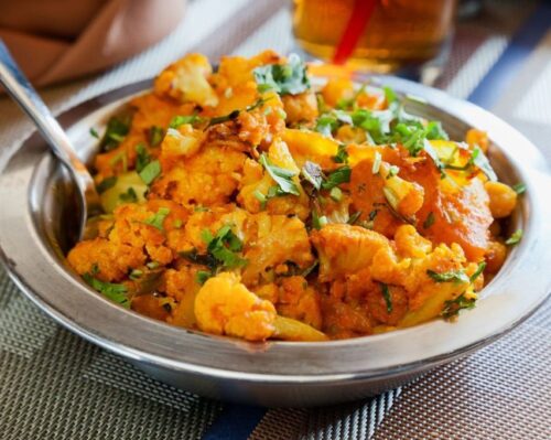 A metal dish of aloo gobi. KERALI RESTAURANT & BAR