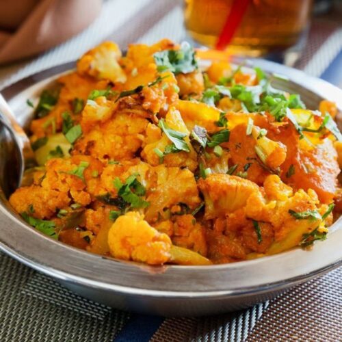 A metal dish of aloo gobi. KERALI RESTAURANT & BAR